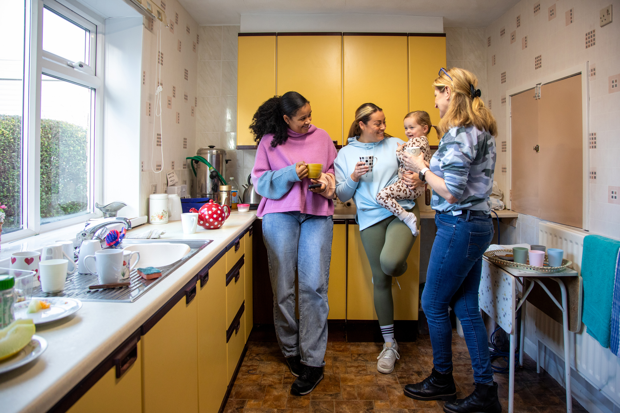 Socialising in a Community Kitchen Full shot of a group of adults standing in a community kitchen smiling and talking to each other, The woman in the middle is holding her baby in her arms. The institute is located in Seghill, Northumberland.